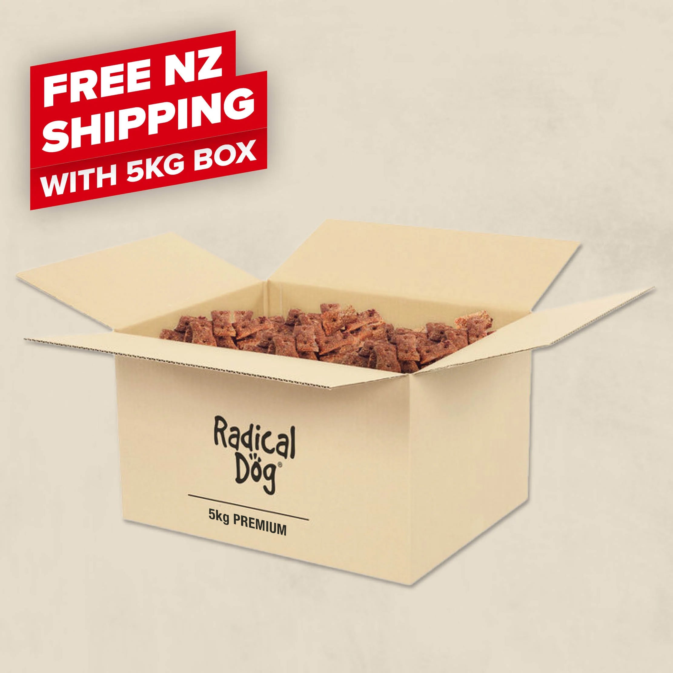 A beige cardboard shipping box labeled 'Radical Dog 5kg PREMIUM' filled with brown dog biscuits, with a red promotional badge reading 'FREE NZ SHIPPING WITH 5KG BOX' on a light beige background.